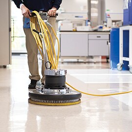 Floor buffing machine polishing a shiny coated floor.