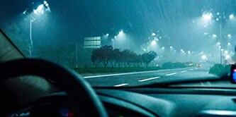 從車內向前方看，夜間下雨的道路，路面上有反光標線
