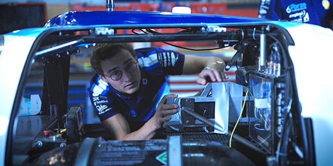 Man working on the inside of a racecar chassis
