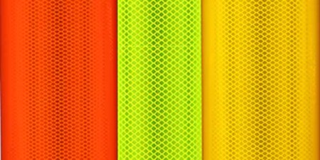Orange, green and yellow fluorescent traffic sheeting reflects light.
