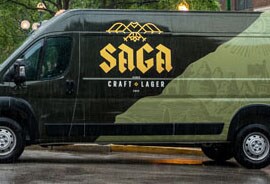 A van has a fleet wrap with a black and green background and a yellow logo.