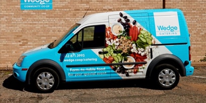 Delivery van with blue fleet wrap that has images of food on the side.
