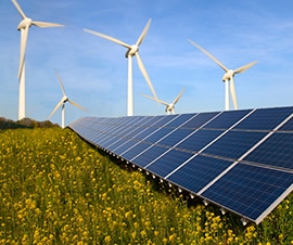 Solar panels and wind turbines producing energy in a field.