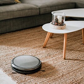 a wireless, robotic vacuum cleaning a living room carpet.