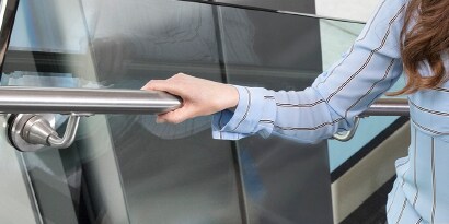 female walking up a staircase holding onto a stainless steel railing
