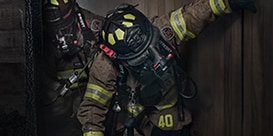 firefighters walking through a smokey building
