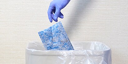 hand with a medical glove throwing away a disposable mop pad.
