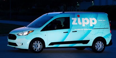 A van’s reflective vehicle wrap glows as it reflects light at night.
