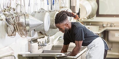 在商業廚房中使用菜瓜布的人
