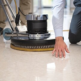 An individual inspects the finish on a recently maintained floor.