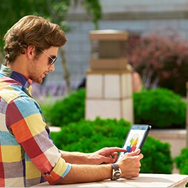 A man outside looking at his electronic tablet that has a bright and colorful display screen.