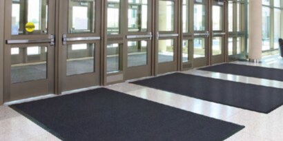 Entrance of a building lobby featuring a floor matting system to trap dirt and moisture from outside..