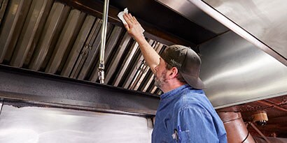 男子在商業廚房使用 3M 去油擦拭巾清潔
