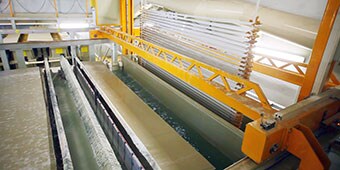 Image of a rack of parts moving between vats during the anodization process
