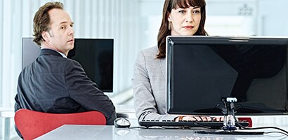 Visual hacker looking over his shoulder at a monitor
