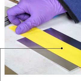 Image of gloved hands applying 3M™ Vinyl Tape 471 prior to an anodizing treatment
