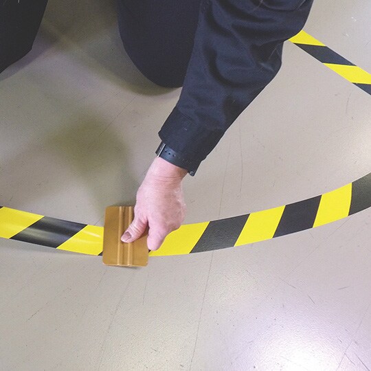 Person applying curved tape lines to floor