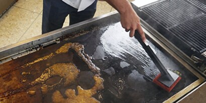 使用3M 百利™ 煎板重垢專用菜瓜布於加熱煎板上
