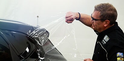A graphic installer removes the Protective Film Layer of 3M™ Wrap Film Series 2080 from the back of a car.
