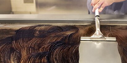 使用刮刀將煎板清潔液從煎板上刮除
