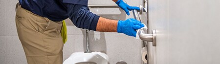 Employee sanitizing bathroom handrail.
