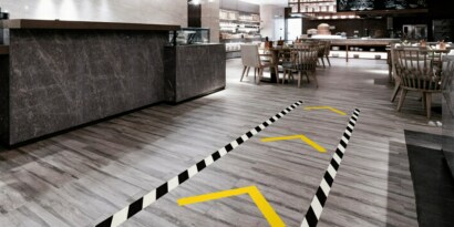 Image of a retail floor marked with a taped lane for traffic and arrows to indicate traffic direction
