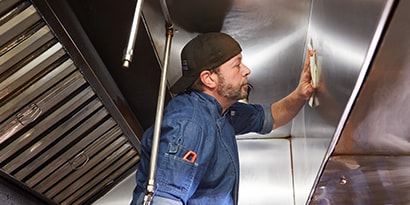 男子站在梯子上安全地使用廚房除油清潔劑
