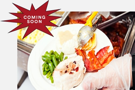 一名餐廳員工戴著餐飲手套，將食物盛裝於盤中。