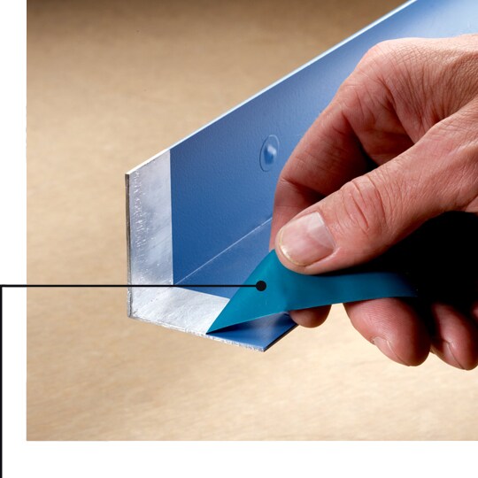 Image of masking tape being removed from L-shaped metal, showing a clean mask line and no adhesive residue