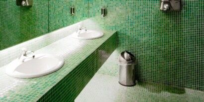 facility's bathroom with clean tile on floor, counter and wall applications.
