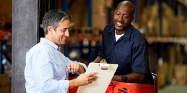 拿著文件夾的工作人員與操作機器的同事討論事情的圖片
