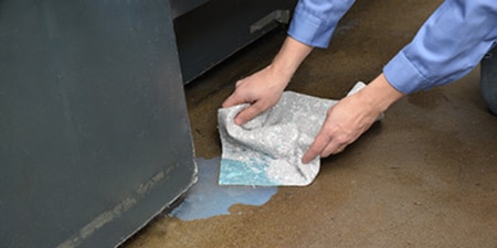 person using 3M spill kit to absorb a liquid spill on the floor.
