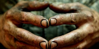 Closeup image of dirty hands with the fingertips pressed together
