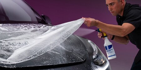 Installer applying 3M paint protection film to a car hood
