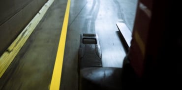 堆高機在以地線標示膠帶劃設動線的倉庫中行駛。
