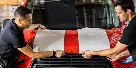 Two installers positioning IJ280 film on hood
