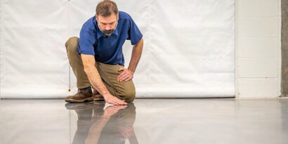 A worker examining the reflective surface of a facility floor.