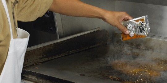 一名廚師使用百利™ 煎板清潔系統清潔平板煎鍋。
