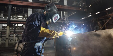 在製造工廠中，焊工穿著防護裝備使用焊槍作業
