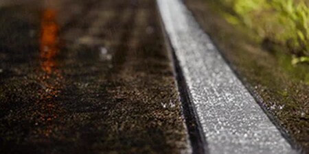 特寫照片顯示了濕滑的道路和高度可見的道路標記。
