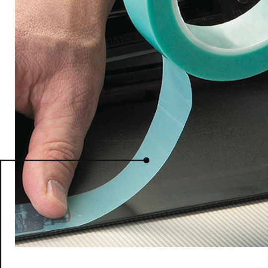 Image of a worker applying non-silicone masking tape to a part