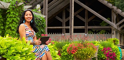  An image of a smiling woman outside holding an electronic tablet.
