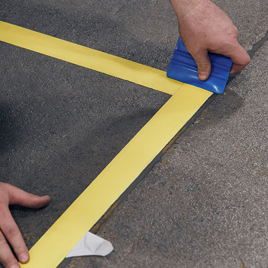 Person applying tape lines to floor